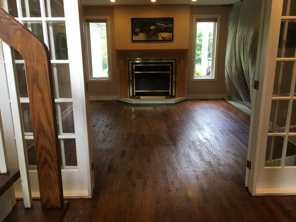 A richly refinished oak floor in a living room with a fireplace and French doors